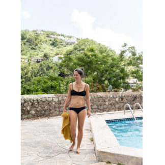 Woman wearing the Well's Bay Bikini pattern from Halfmoon Atelier on The Fold Line. A reversible bikini pattern made in swimwear fabrics, featuring under-bust darts, thin shoulder straps, and back ties. The bottoms are low-rise hipsters with full coverage.