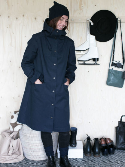 Woman wearing the Hoodie Parka Coat sewing pattern by The Assembly Line. An A-line shaped coat pattern made in canvas, cotton twill or denim featuring snap button closing, large front pockets and hood.
