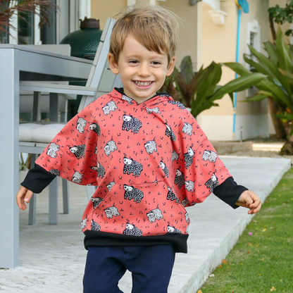 Child wearing the Child/Baby Poncho Hoodie sewing pattern from Elemeno Patterns on The Fold Line. A winged hoodie style poncho pattern made in cotton knit fabrics, featuring hem and wrist cuffs, relaxed fit and hood.