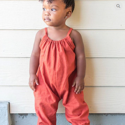 Child wearing the Child/Baby Boho Romper sewing pattern from Elemeno Patterns on The Fold Line. A romper pattern made in woven or knit fabrics, featuring tie shoulder straps, roomy fit, sleeveless, full length leg with elasticated ankles.