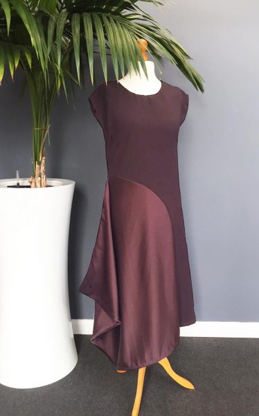Photo showing the Flounce Dress sewing pattern from Sew Different on The Fold Line. An asymmetric midi-length dress pattern made in crepe or jersey fabrics, featuring a round neck, cap sleeves, fitted through the bust, and curved side seam.