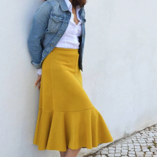 Woman wearing the Linea A-Line Skirt sewing pattern from Wardrobe by Me on The Fold Line. A skirt pattern made in light to medium weight knit jersey fabrics, featuring a four gored skirt, elasticated waist, midi length hem and circular voilant sewn to the hem.