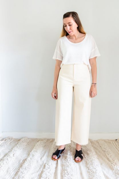 Woman wearing the Parasol Trousers sewing pattern by Ensemble. A trouser pattern made in light to medium weight woven fabrics, featuring a high waist, slanted front pockets, no side seams and front zipper closure.