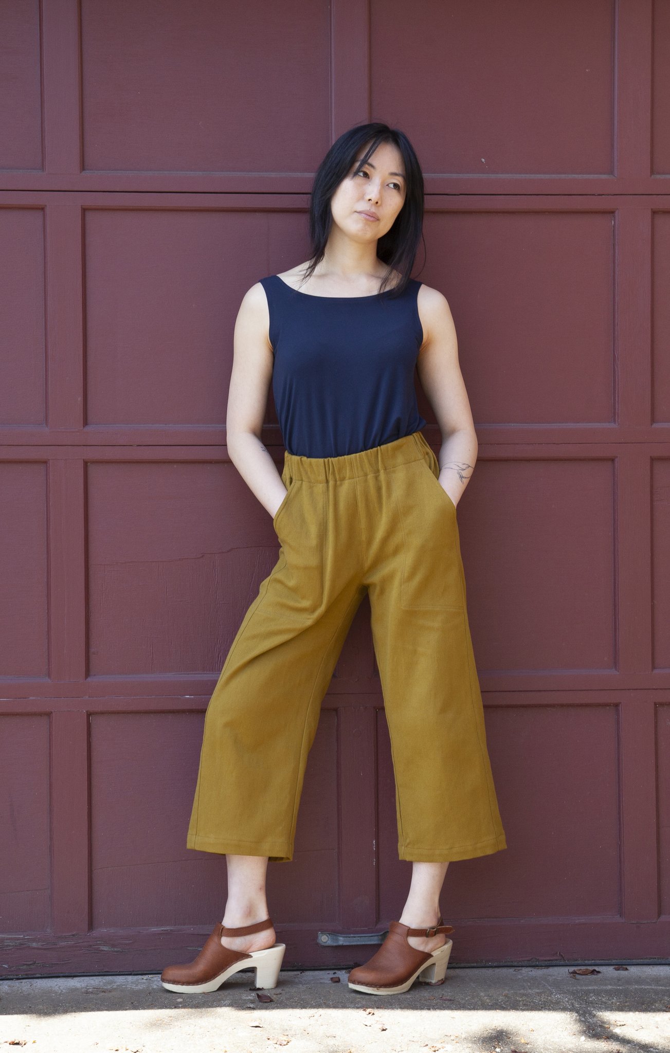 Woman wearing the Free Range Slacks sewing pattern from Sew House Seven on The Fold Line. A trouser pattern made in cotton/linen blends, rayon/linen blends, denim, tencel twill, cotton poplin or gabardine fabrics, featuring a straight cropped leg, high waist with elastic, front slash pockets and relaxed fit.