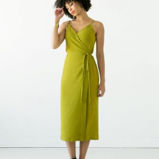 Woman wearing the Calvin Wrap Dress sewing pattern by True Bias. A sleeveless dress pattern made in linen, chambray, rayon or cotton fabric featuring a low V-neck, adjustable shoulder straps and waist tie closure.
