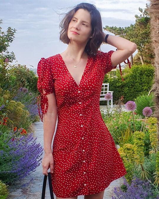 Woman wearing the Etoile Dress sewing pattern by French Poetry. A dress pattern made in silk crepe, viscose, polyester crepe or linen fabrics, featuring a deep V-neck, button front closure, front and back darts and gathered short sleeves with self-fabric ties.