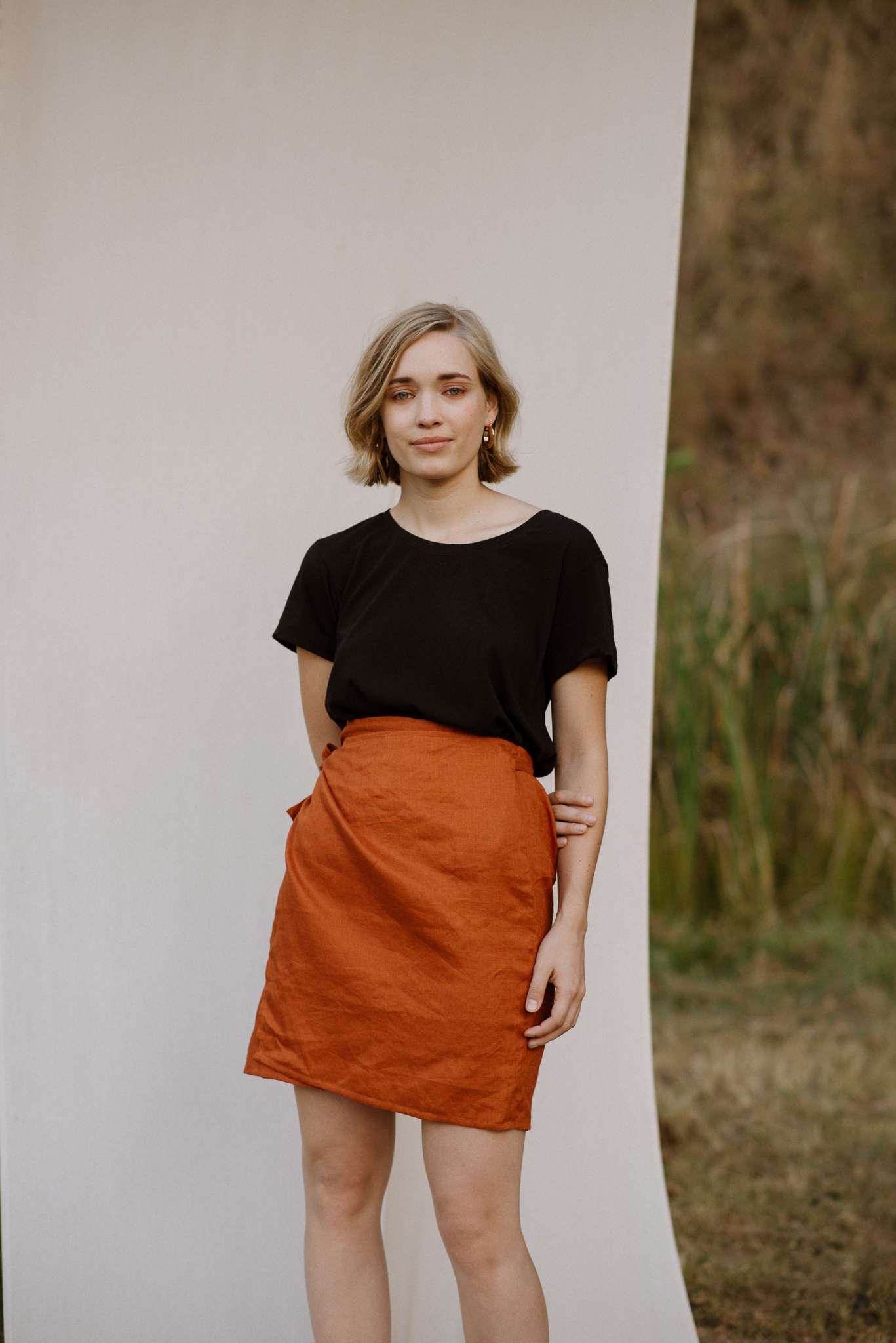 Woman wearing the Bellbird Wrap Skirt sewing pattern by Common Stitch. A wrap skirt pattern made in linen fabrics, featuring a tie waist and mini length.