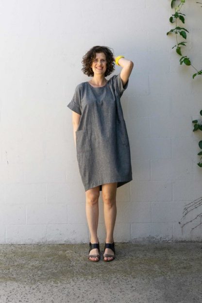 Woman wearing the Lou Box Dress 1 sewing pattern from Sew DIY on The Fold Line. A dress pattern made in medium weight knit or woven fabrics, featuring a cocoon silhouette, scoop neck, short cuff sleeves, patch pockets and a knee-length skirt.