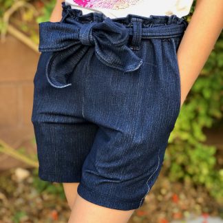 Child wearing the Lola Shorts sewing pattern from 5 out of 4 Patterns on The Fold Line. A shorts pattern made in rayon challis, crepe, satin charmeuse, peach skin or some poly blend fabrics, featuring a paper-bag waist with self-fabric tied belt, relaxed fit and slash pockets.