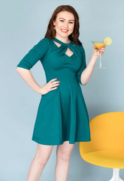 Woman wearing the Martini Twist Dress sewing pattern from Our Lady of Leisure on The Fold Line. A dress pattern made in medium-weight, medium stretch knit fabrics, featuring a twisted neckline, ¾ length sleeves, above knee length, fitted bodice, flared skirt and invisible back zipper.