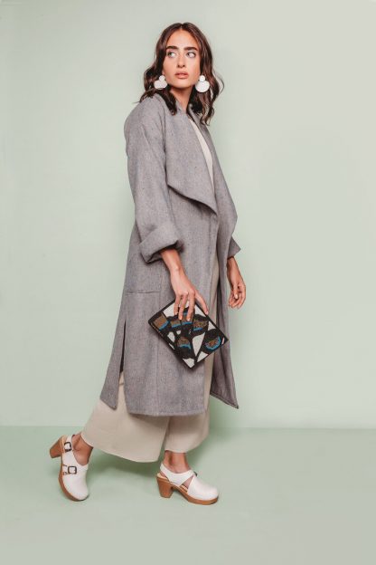 Woman wearing the Cambria Duster Coat sewing pattern by The Assembly Line. A shin length coat pattern made in rayon twill, gabardine, or light wool fabric featuring a dramatic, wide draped shawl-style collar, and side pockets.