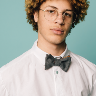 Man wearing the Ola Bow Tie sewing pattern from Melilot on The Fold Line. A bow tie pattern made in cotton, wool, silk or rayon fabrics, featuring a reversible style and one length of fabric.