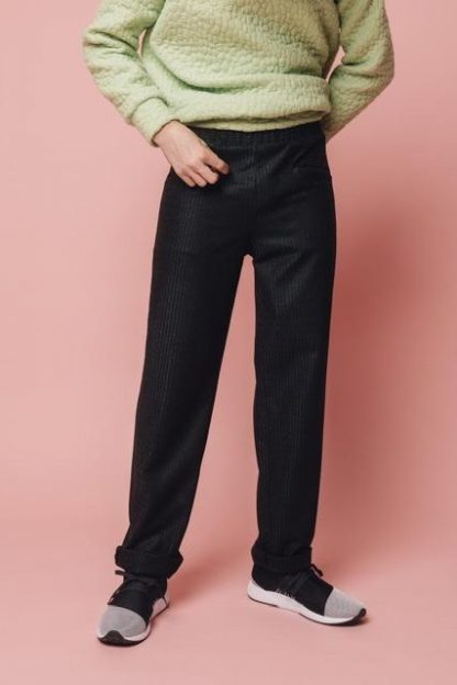 Man wearing the Huy Trousers sewing pattern from Melilot on The Fold Line. A unisex trouser pattern made in mid-weight cotton, linen or wool fabrics, featuring an elastic waist, front and back pockets, and narrow legs.