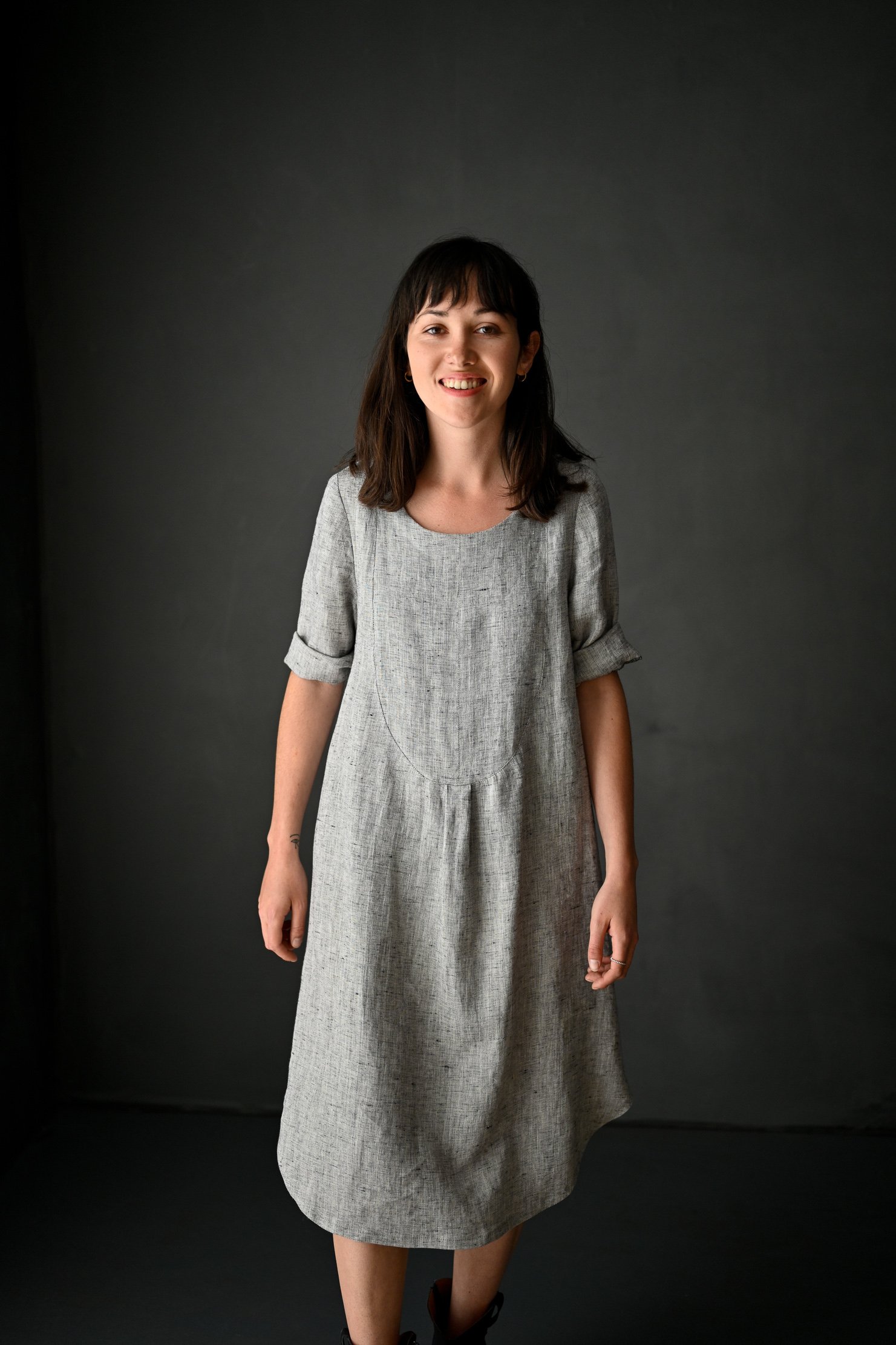 Woman wearing the Dress Shirt sewing pattern by Merchant and Mills. A dress pattern made in cotton, linen, lightweight denim, silk or corduroy fabric featuring elbow length rolled up sleeves, loose fit and round neckline.