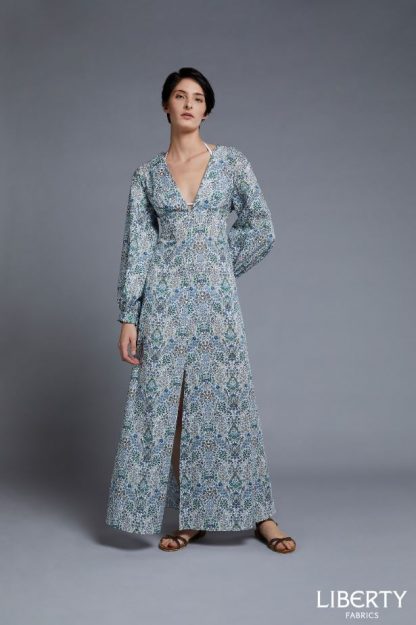 Woman wearing the Beatrix Maxi Dress sewing pattern by Liberty Sewing Patterns. A maxi dress pattern made in cotton or silk fabrics, featuring a deep V-neckline, long sleeves, empire waist and centre front slit.