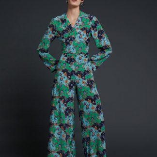 Woman wearing the Florence Palazzo Suit sewing pattern by Liberty Sewing Patterns. A trouser and wrap blouse pattern made in cotton, silk, linen or light velvet fabrics, featuring wide legged trousers that are loose fitting through the hips, wide front and back yokes, pockets and back zipper. The blouse has long sleeves, waist ties, V-neck and notched collar.