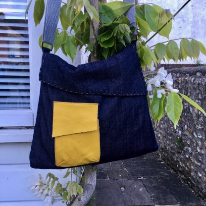 The Almost Square Bag sewing pattern by Dhurata Davies Patterns. A messenger style bag pattern made in medium weight woven fabric, featuring a front patch pocket, angled flap and large zipped pocket on the back.