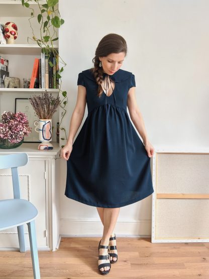 Woman wearing the Paulette Dress sewing pattern by Camimade. A dress pattern made in crepe, viscose, rayon, cotton lawn or cotton sateen fabrics, featuring a Peter Pan collar, front keyhole, cap sleeves and a gathered skirt that is pregnancy friendly due to its empire line. It closes with a side invisible zipper.