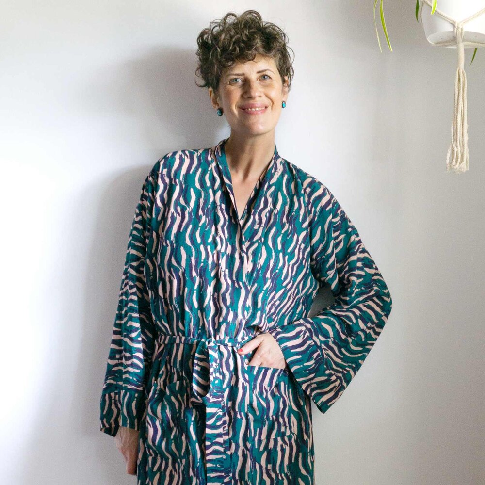Woman wearing the Unisex Draft-It-Yourself Tasi Robe sewing pattern from Sew DIY on The Fold Line. A robe pattern made in light to medium weight woven or knit fabrics, featuring a relaxed fit, patch pockets, tie belt, full length sleeves with hem bands.