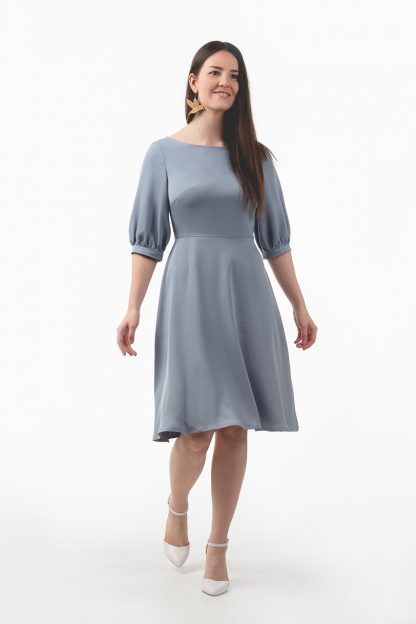 Woman wearing the Veera Dress sewing pattern from Tessa Roosa on The Fold Line. A dress pattern made in lyocell, cupro, linen, double gauze, lawn or rayon fabrics, featuring an invisible back zipper, puff sleeves, boat neck and a knee length A-line skirt.