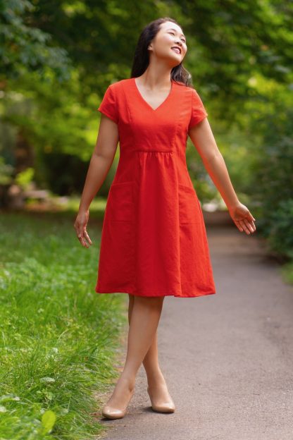 Woman wearing the Celeste Dress sewing pattern from Itch to Stitch on The Fold Line. A dress pattern made in linen, linen blends, cotton blends, chambray and poplin fabrics, featuring a relaxed-fit, knee length, V neck, front and back princess seams, high-waisted centre-front gathers, front pockets, short sleeves, and A - DD cup sizes.