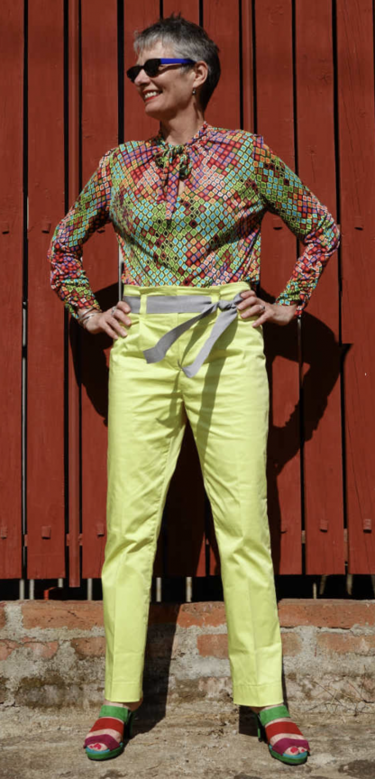 Woman wearing the Senorita Blouse sewing pattern by Alice and Co Patterns. A blouse pattern made in slinky silk jersey, bamboo, synthetic or viscose jersey or a fine wool knit fabric, featuring a front neck slit and bow tie and long sleeves that are ruched from wrist to elbow.