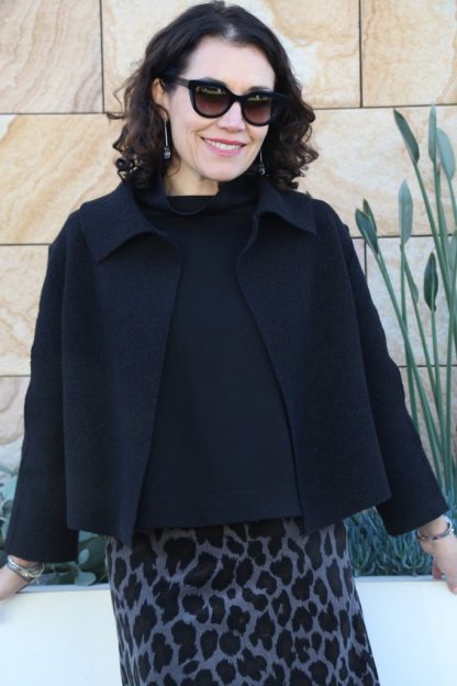 Woman wearing the Verona Jacket sewing pattern from Tessuti Fabrics on The Fold Line. A jacket pattern made in boiled wool and wool blend fabrics, featuring a cropped length, boxy style, extended shoulders, collar, front shoulder darts, two-piece bracelet length sleeves, and raw edges.
