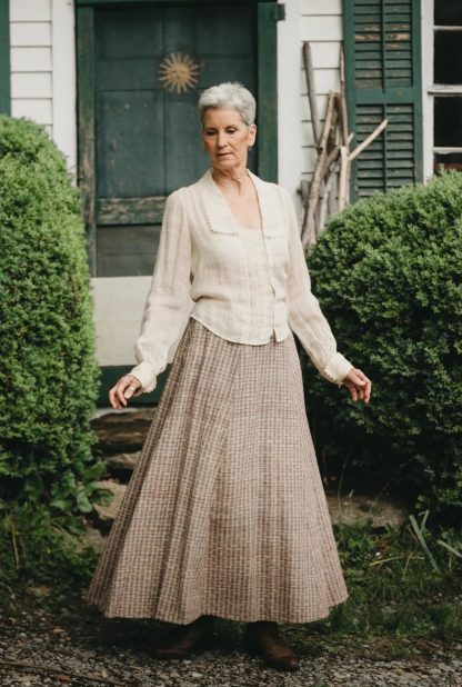 Woman wearing the 209 Walking Skirt sewing pattern from Folkwear on The Fold Line. A gored skirt pattern made in medium to heavyweight cottons and blends, linen, silk, lightweight wool, thin-wale corduroy, and velvet fabrics, featuring a fitted front, gathered back, narrow waistband, midi length, and center back snap placket.