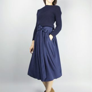 Woman wearing the Arpege Skirt sewing pattern by Atelier Scammit. A full skirt pattern made in very light to light weight batiste, chambray or double gauze fabrics, featuring a back button closure, button and loop fastenings and a long tie belt.