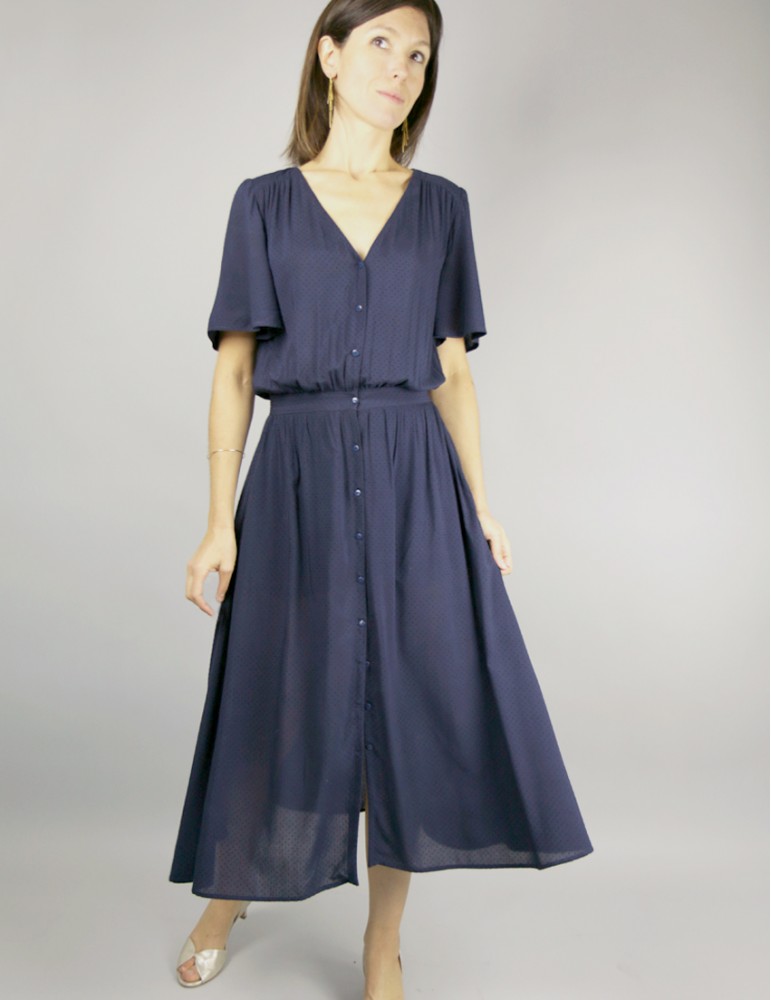 Woman wearing the Harmonie Dress sewing pattern by Atelier Scammit. A waisted, dress pattern made in very light to medium weight batiste, crepe, light denim or viscose fabrics, featuring a V-neck, short sleeves, in-seam pockets and button front closure.