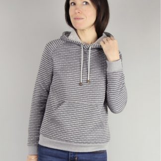 Woman wearing the Icone Sweatshirt and Cardigan sewing pattern by Atelier Scammit. A sweatshirt pattern made in medium to heavy weight sweatshirt fabric or boucle knits, featuring a slightly curved raglan sleeve, ample hood, kangaroo pockets and full length cuffed sleeves.
