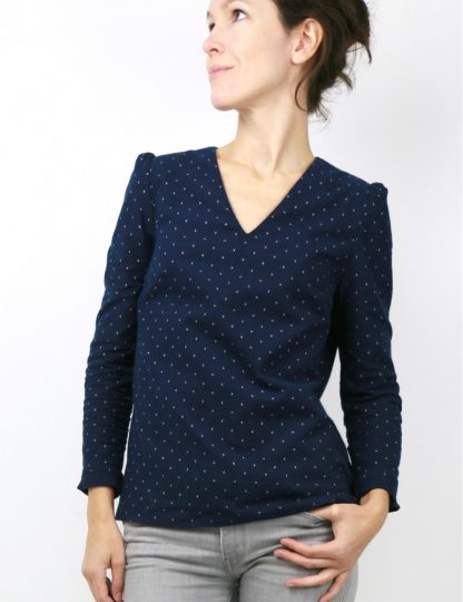 Woman wearing the Idylle Blouse sewing pattern by Atelier Scammit. A blouse pattern made in light to medium batiste, crepe, light denim or flannel fabrics, featuring a V-neck, long sleeves, pin-tuck shoulders and button back closure.