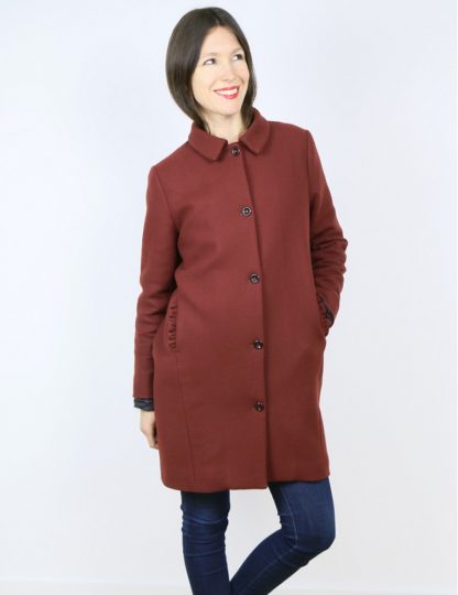 Woman wearing the Merci Coat sewing pattern by Atelier Scammit. A coat pattern made in medium to thick woollens, jacquard or gabardine fabrics, featuring front button closure, collar, pockets and above knee length.