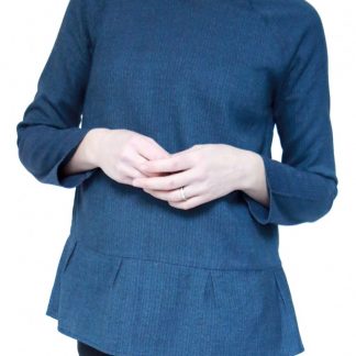 Woman wearing the Stockholm Blouse sewing pattern by Atelier Scammit. A blouse pattern made in very light to medium weight jersey (or woven fabric, one size larger) fabrics, featuring long, raglan sleeves, round neck and a back button and loop closure.
