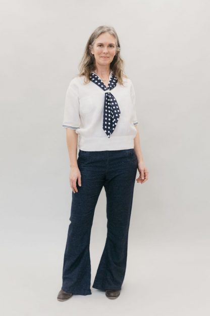 Woman wearing the 229 Unisex Sailor Pants sewing pattern from Folkwear on The Fold Line. A trouser pattern made in wool melton, denim, twill, cotton duck, linen, flannel, or light to medium weight canvas fabrics, featuring a high-waisted, bell bottom legs, buttoned front flap closure, lace-up back eyelet gusset, back welt pocket, inner leg godet, and hidden coin pocket in front waistband seam.