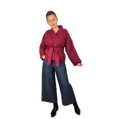 Woman wearing The Overlap Jacket sewing pattern by Dhurata Davies Patterns. A wrap jacket pattern made in lightweight breezy linen to cosy wool fabric, featuring a belt and loops, patch pockets and hip length.