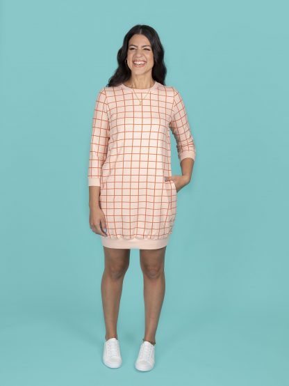 Woman wearing the Billie Dress sewing pattern from Tilly and the Buttons on The Fold Line. A cape pattern made in sweatshirt fleece, French terry, ponte, double knit, interlock or sweater knit fabrics, featuring a relaxed fit, crew neckline, cuffed straight ¾ sleeves, above knee length, and cutaway pockets.