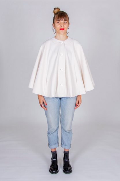 Woman wearing the Harry Cape sewing pattern from I AM Patterns on The Fold Line. A cape pattern made in boiled wool, wool gabardine, melton, bouclé or jacquard. fabrics, featuring a circular silhouette, in-seam pockets, flat collar, fully lined, front button placket.