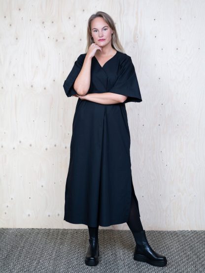 Woman wearing the Kaftan Dress sewing pattern from The Assembly Line on The Fold Line. A dress pattern made in cotton, silk, linen, crepe de chine or tencel fabrics, featuring a relaxed fit, elbow length raglan sleeves, overlap V-neck which creates a pleat in the front, side slits and in-seam pockets.
