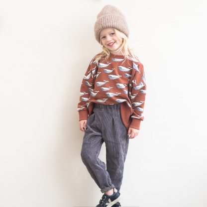 Child wearing the Child/Teen Casper Sweater sewing pattern from WISJ Design on The Fold Line. A unisex sweater pattern made in stretch knit fabrics, featuring an oversized fit, high-low hem, round neck, long sleeves, ribbed cuffs, hem and neckband.