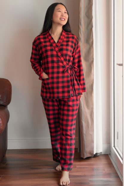 Woman wearing the Pine Cove Pajamas sewing pattern from Itch to Stitch on The Fold Line. A pyjamas pattern made in flannel, silk, satin, double gauze, broadcloth, chambray and cotton lawn fabrics, featuring a relaxed fit, hip-length top has dropped shoulders, long sleeves, side splits, patch pocket, banded overlapped front with tie closures. The long pants have an elastic waist.