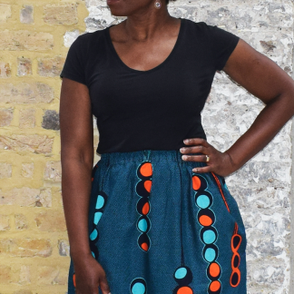 Woman wearing the Althea A-Line Skirt sewing pattern by Dovetailed. A skirt pattern made in wax print, cottons, gauze, linen, silks, chambray, georgette or poplin fabrics, featuring an A-line silhouette, elasticated waistband and side pockets.