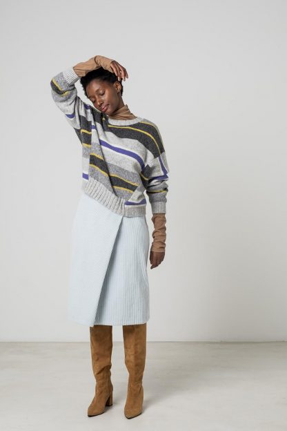 Woman wearing the Maddie Skirt sewing pattern from Fibre Mood on The Fold Line. A faux wrap skirt pattern made in wool, corduroy, denim or crepe fabrics, featuring a waistband with snap button closure and knee length hem.