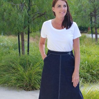 Woman wearing the No-Zip Skirt sewing pattern by Blue Dot Patterns. An A-line skirt pattern made in denim, twill, corduroy, suitings, sateen, poplin or linen fabrics, featuring a fitted waist, slash pockets, button and hook and eye closure.