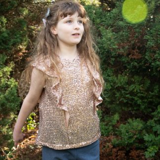 Child wearing the Baby/Child/Teen Alice Top sewing pattern by Bobbins and Buttons. A sleeveless, top pattern made in cottons, double gauze or linen fabrics, featuring a deep ruffle that runs over the shoulder and keyhole back opening.