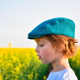 Child wearing the Baby/Child/Adult Fell and Dale Flat Cap sewing pattern by Wavers and Wild. A cap pattern made in wool tweed, wool blends, corduroy, denim or heavier linen fabrics, featuring optional elastic at the back and a brim or peak.