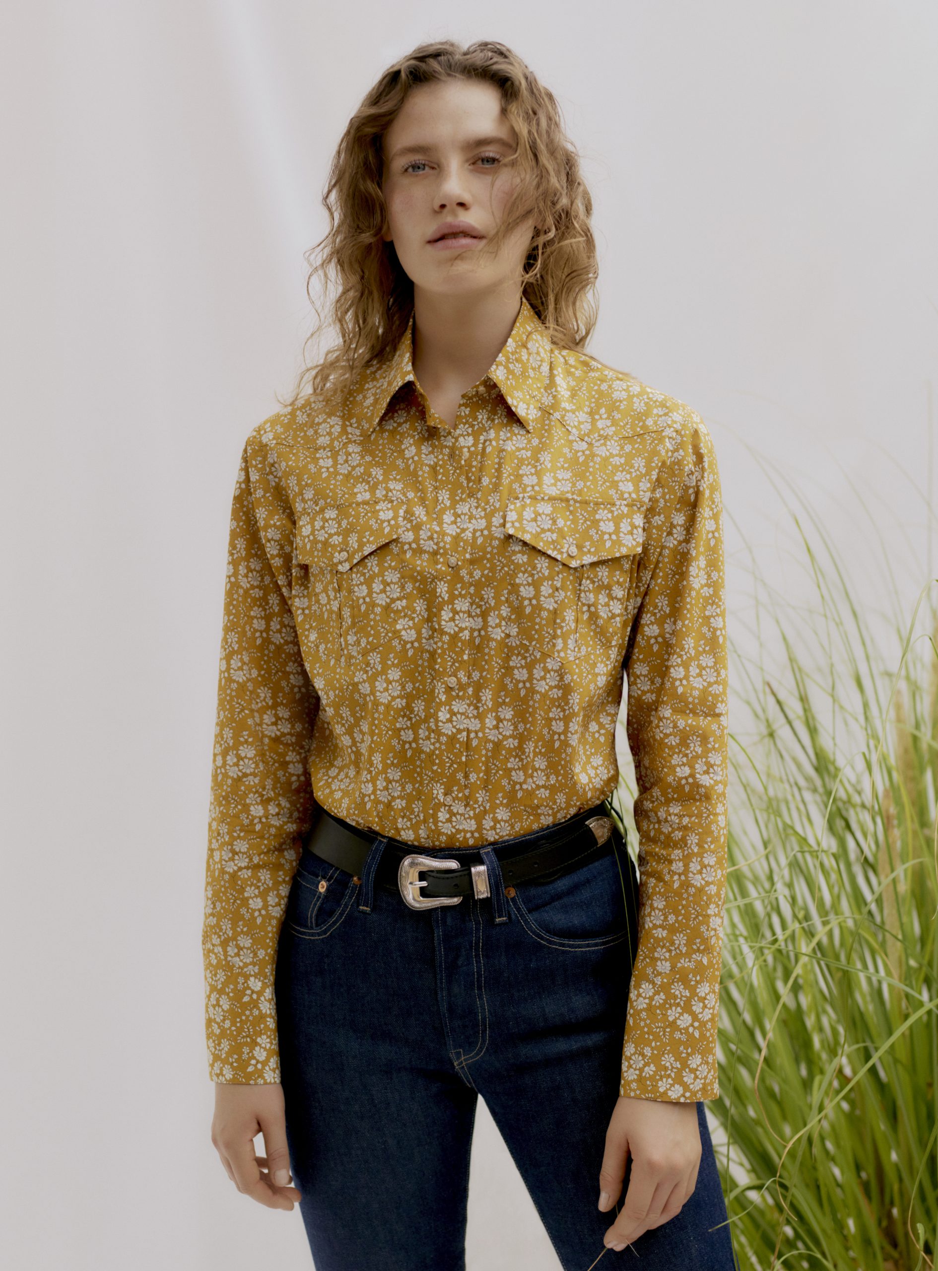Woman wearing the Unisex Camargue Cowboy Shirt sewing pattern by Liberty Sewing Patterns. A shirt pattern made in cotton, or chambray fabrics, featuring a classic shirt collar, long sleeves with button cuffs, patch chest pockets and button front closure.
