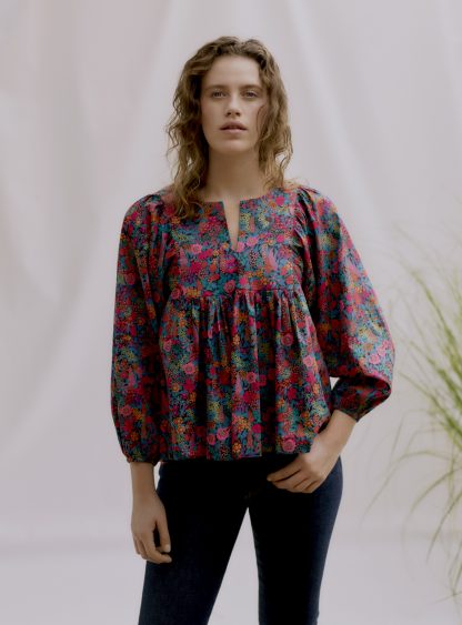 Woman wearing the Esther Tunic Top sewing pattern by Liberty Sewing Patterns. A smock top pattern made in cotton, crepe de chine or silk fabrics, featuring bracelet length gathered sleeves and jewel neckline with V slit.