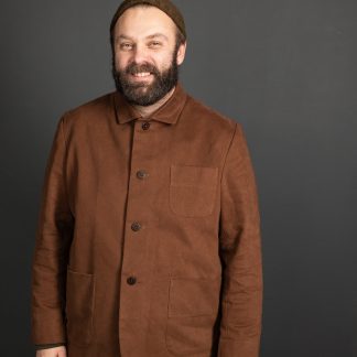 Man wearing the Men's Foreman Jacket sewing pattern from Merchant and Mills on The Fold Line. A jacket pattern made in oilskin, cotton canvas, twill, denim, linen corduroy or woollen tweed fabrics, featuring a boxy cut, two piece sleeves, square collar, breast pocket, two hip pockets, front button closure and full length sleeves.