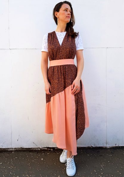 Woman wearing the Lynn Pinafore sewing pattern by Vanessa Hansen. A pinafore dress pattern made in cotton lawn, viscose challis and viscose blends, crepe de chine or charmeuse fabrics, featuring a V-neck, diagonal gathered tier, asymmetrical hem, left side slip, waistband and gathered bodice.